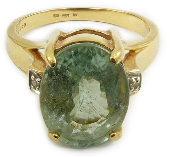 A modern 18ct gold and oval cut pale green tourmaline set dress ring, with two stone diamond chip set shoulders